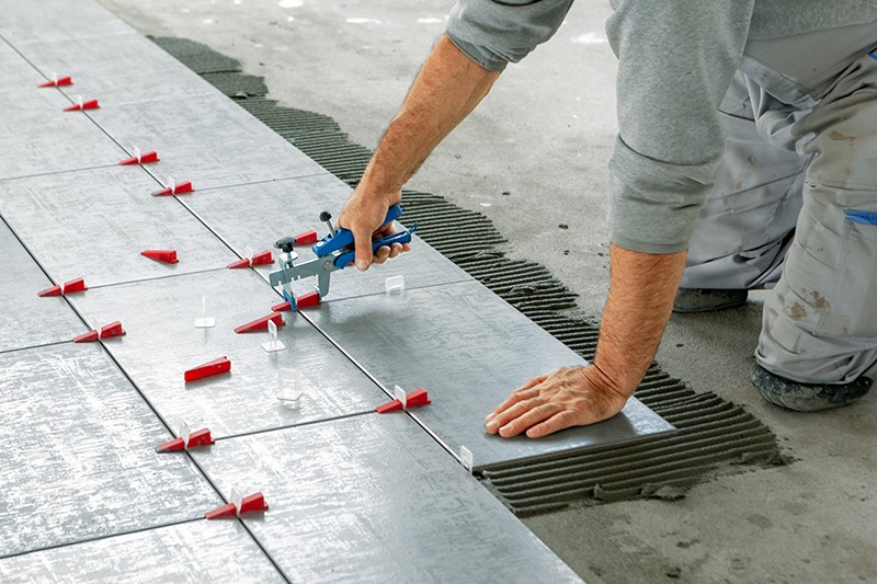 Worker installing tile flooring into new building | The L&L Company
